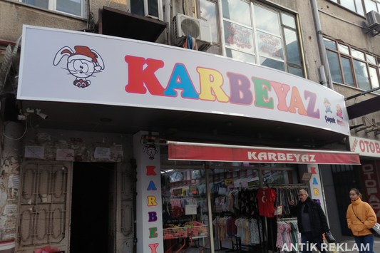 Karbeyaz çocuk giyim mağazası renkli vinil tabela dış mekan cephe görünümü